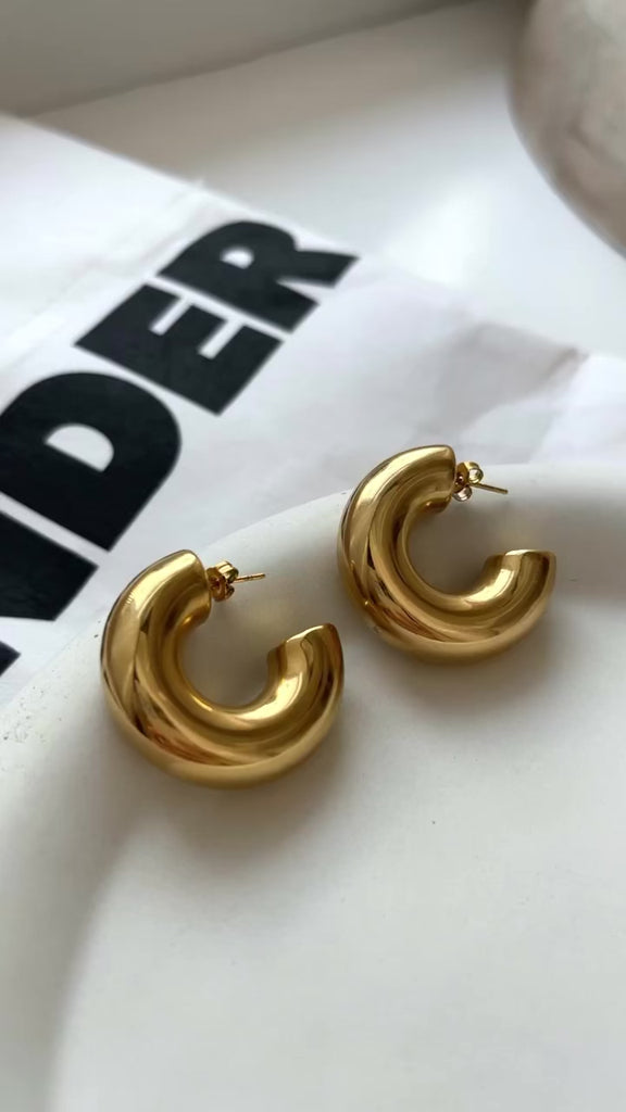 Gold chunky hoop earrings with a glossy finish, designed as bold statement pieces for stylish accessorizing.